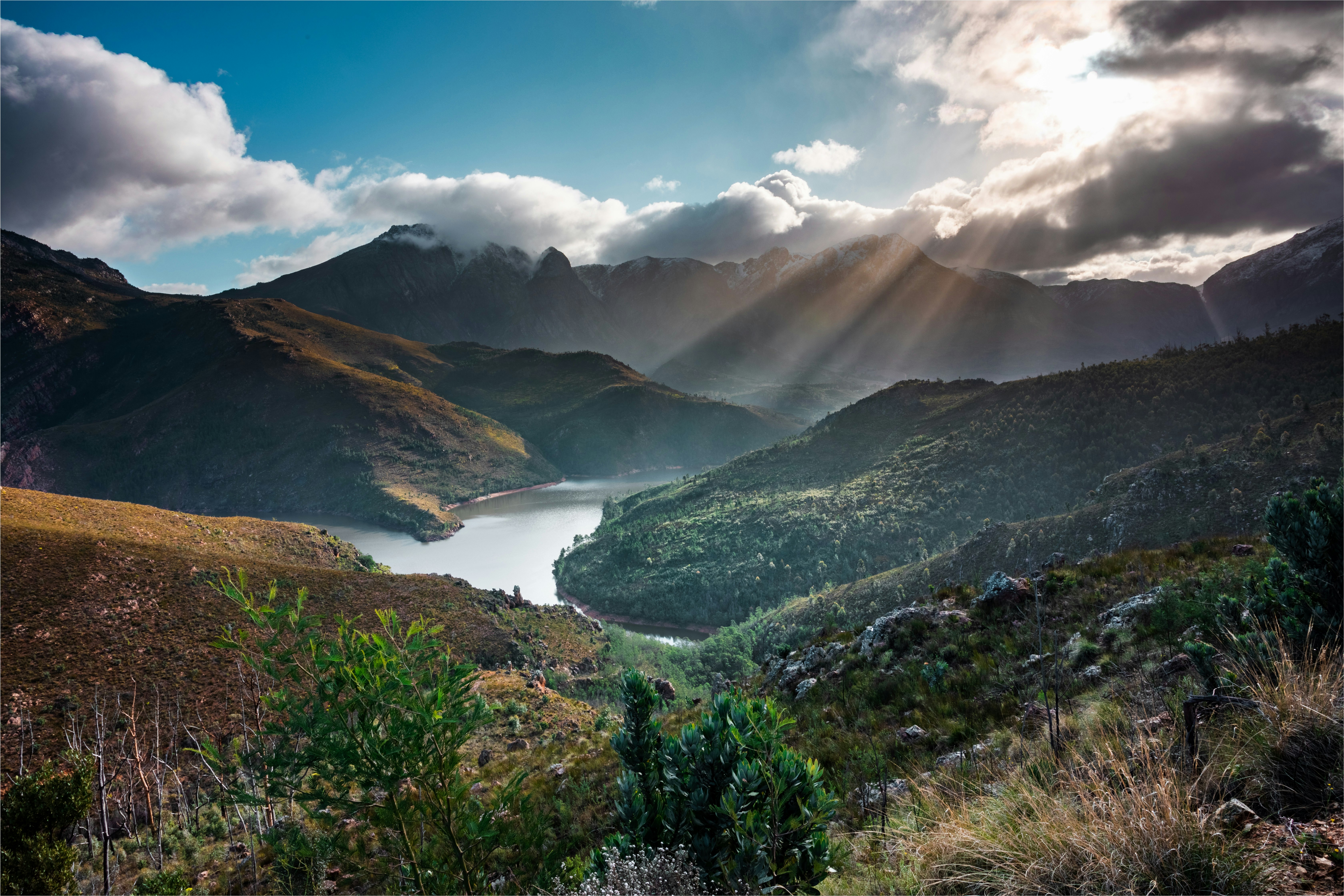 green mountains near body of water under blue sky during daytime